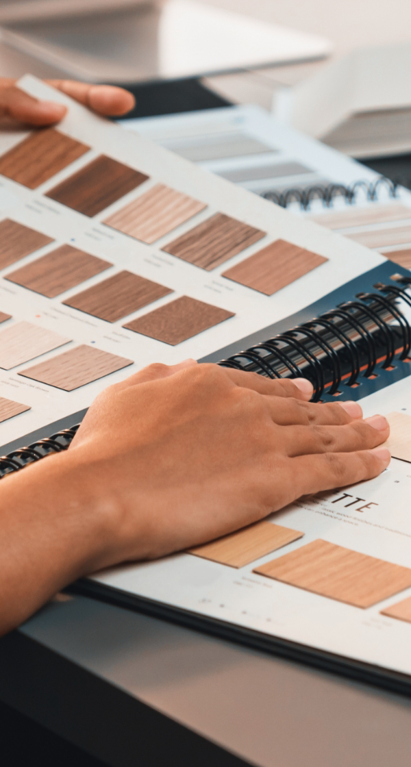 A person browses through a catalog of wood samples, envisioning the perfect finishes for their space. With the guidance of a luxury home remodeling company, they explore options that will transform their vision into reality with effortless elegance.