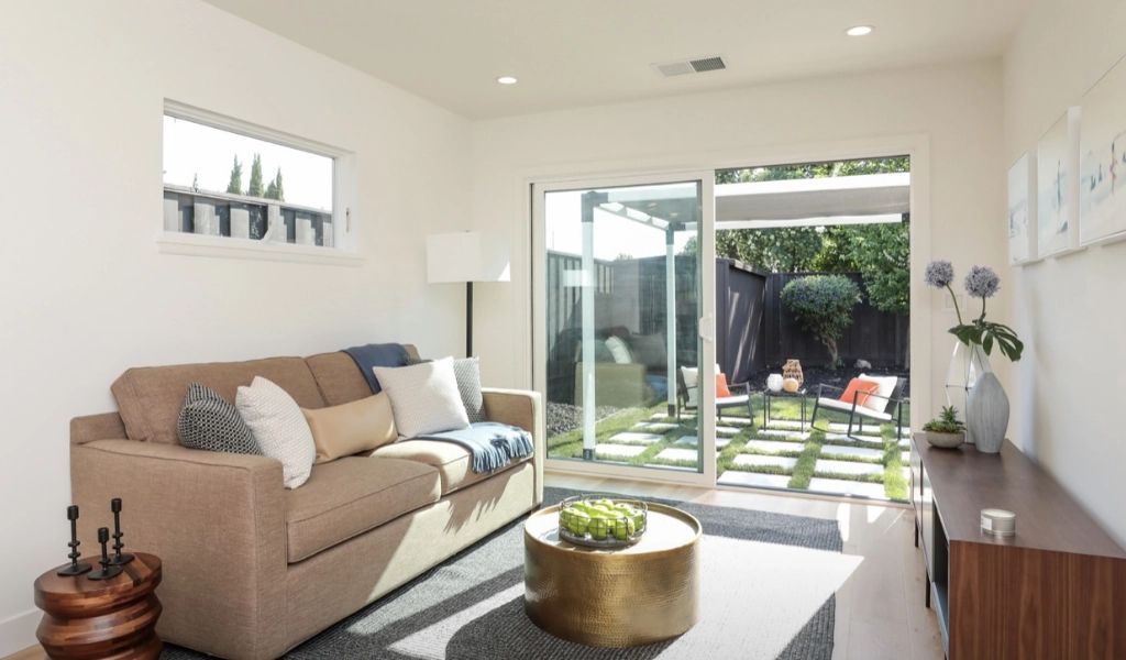 A modern living space with a brown couch, gray rug, and large windows letting in natural light.
